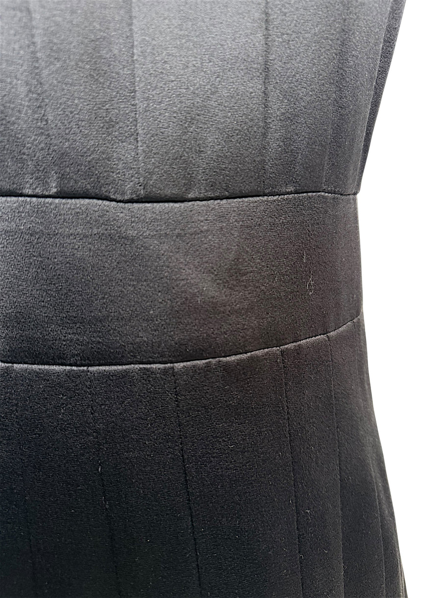 Close-up fabric detail of vintage Chanel black satin dress showing texture and subtle sheen.