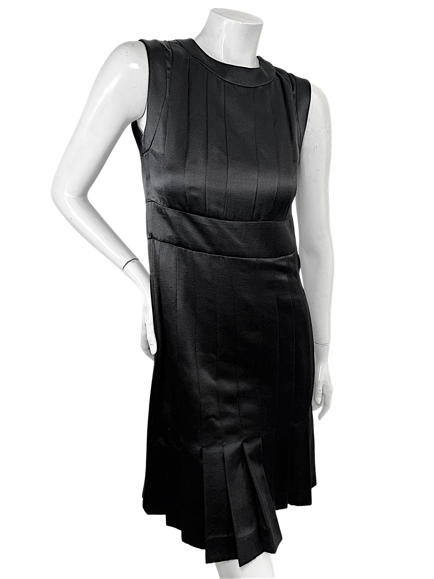 Angled front view of vintage Chanel black satin pleated cocktail dress with architectural tailoring.
