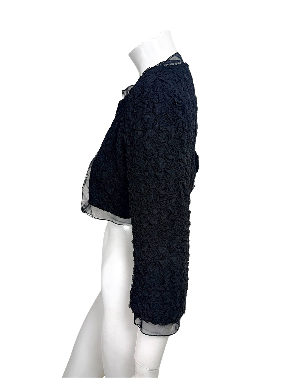 Side profile of Chanel black cropped bolero jacket showing structured silhouette and 3/4 sleeve