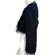Side profile of Chanel black cropped bolero jacket showing structured silhouette and 3/4 sleeve