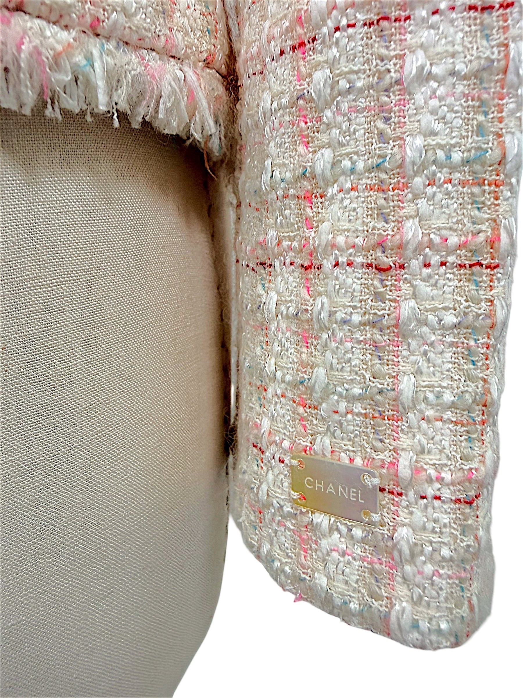Close-up of signature Chanel logo plaque affixed to the sleeve of the Cruise 2004 ivory fantasy tweed jacket.