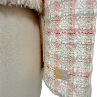 Close-up of signature Chanel logo plaque affixed to the sleeve of the Cruise 2004 ivory fantasy tweed jacket.