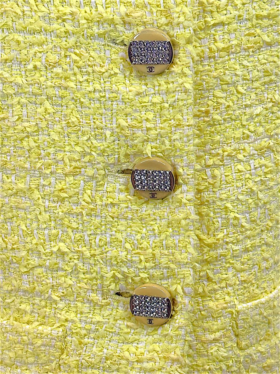 Close-up detail of crystal CC logo buttons on Chanel Cruise 2012 yellow bouclé tweed runway jacket
