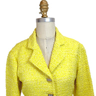Close front upper view of Chanel Cruise 2012 yellow bouclé tweed runway jacket featuring structured lapel collar and jeweled CC buttons