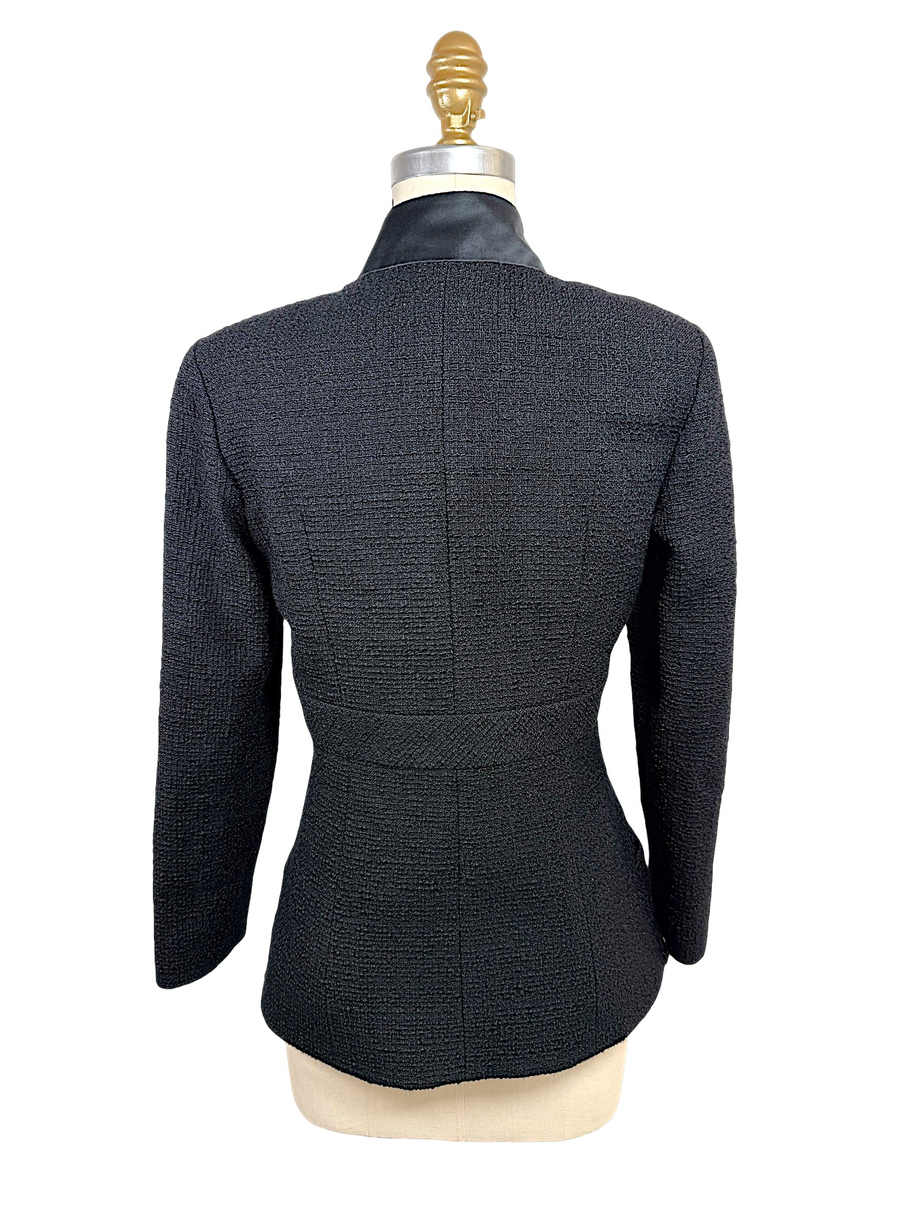 Rear view of the Chanel Cruise 2017 textured black jacket showcasing the fitted tailoring, center seam construction, and satin collar.