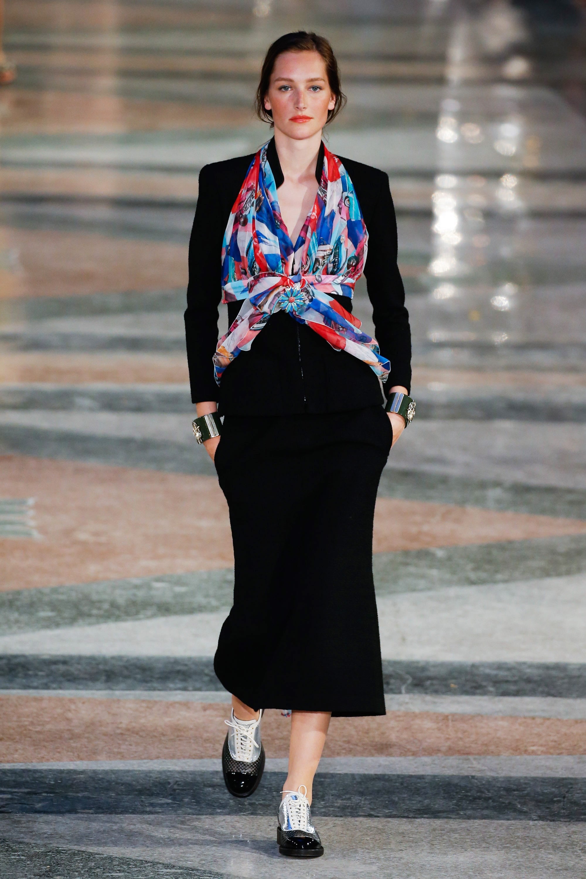 Editorial runway reference of Chanel Cruise 2017 Look 32 under Karl Lagerfeld featuring the original styling of the documented black textured tailored jacket with a colorful printed silk scarf.