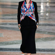 Editorial runway reference of Chanel Cruise 2017 Look 32 under Karl Lagerfeld featuring the original styling of the documented black textured tailored jacket with a colorful printed silk scarf.