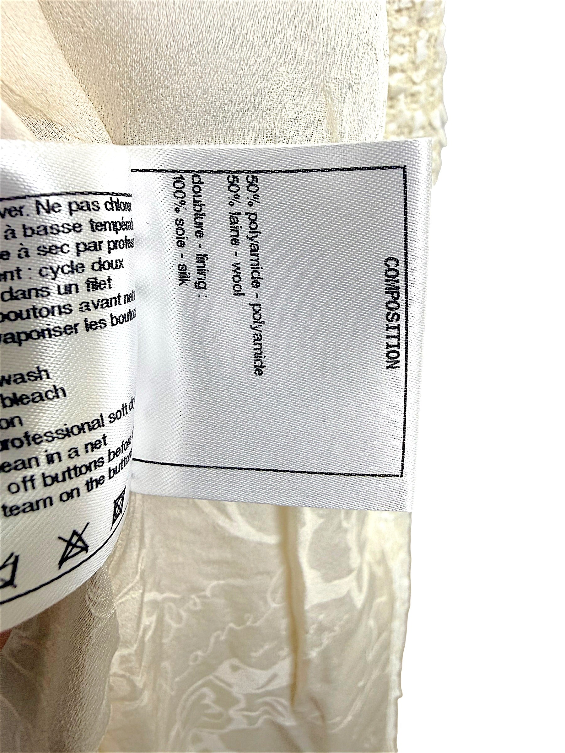 Interior composition and care label detailing the premium fabric blend and silk lining used in the Chanel Cruise 2019 Runway Look 26 ivory fantasy tweed jacket.
