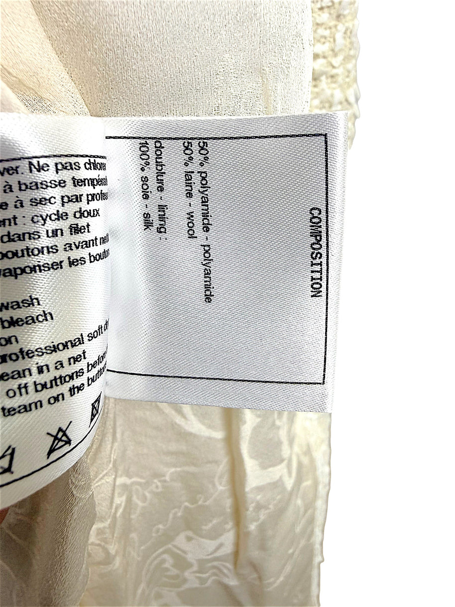 Interior composition and care label detailing the premium fabric blend and silk lining used in the Chanel Cruise 2019 Runway Look 26 ivory fantasy tweed jacket.