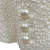 Close-up of the three original pearl-effect La Pausa CC buttons on the sleeve cuff of the Chanel Cruise 2019 Runway Look 26 fantasy tweed jacket.