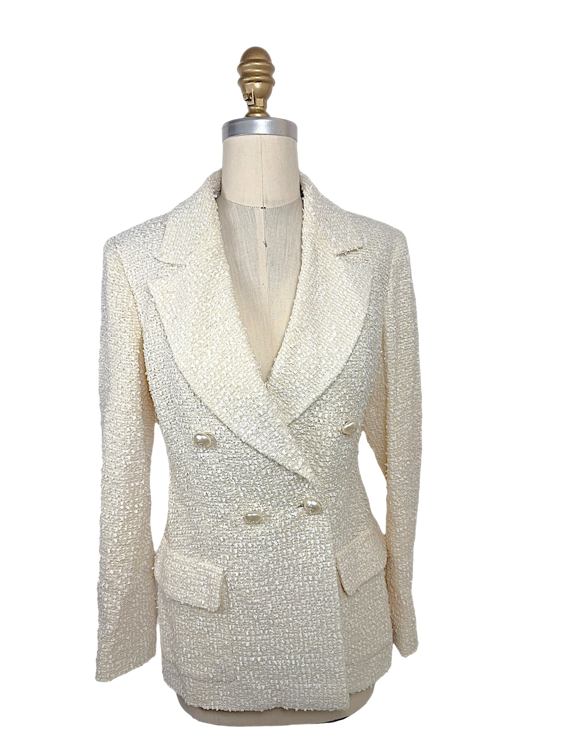 Front view of an authentic Chanel Cruise 2019 Runway Look 26 ivory fantasy tweed double-breasted jacket with oversized shawl lapels and pearl-effect La Pausa CC buttons.