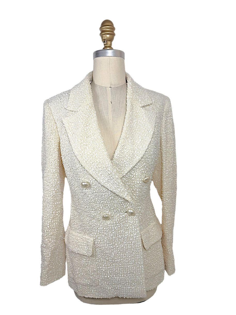 Front view of an authentic Chanel Cruise 2019 Runway Look 26 ivory fantasy tweed double-breasted jacket with oversized shawl lapels and pearl-effect La Pausa CC buttons.