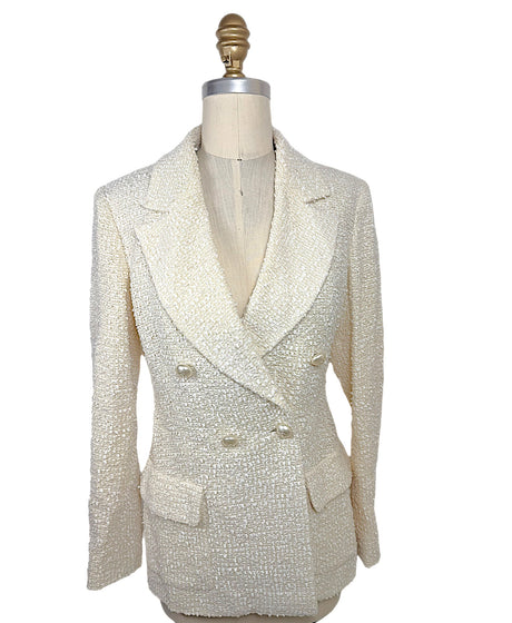 Front view of an authentic Chanel Cruise 2019 Runway Look 26 ivory fantasy tweed double-breasted jacket with oversized shawl lapels and pearl-effect La Pausa CC buttons.