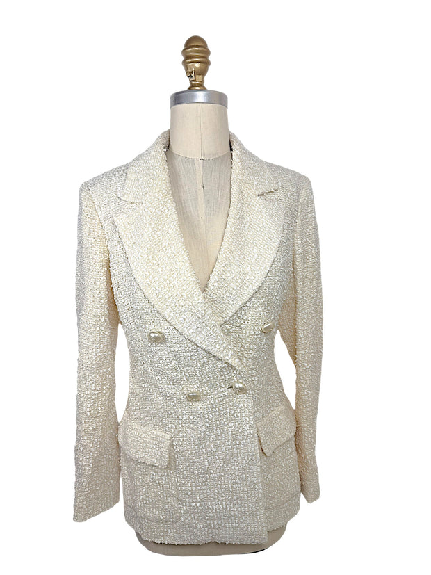 Front view of an authentic Chanel Cruise 2019 Runway Look 26 ivory fantasy tweed double-breasted jacket with oversized shawl lapels and pearl-effect La Pausa CC buttons.