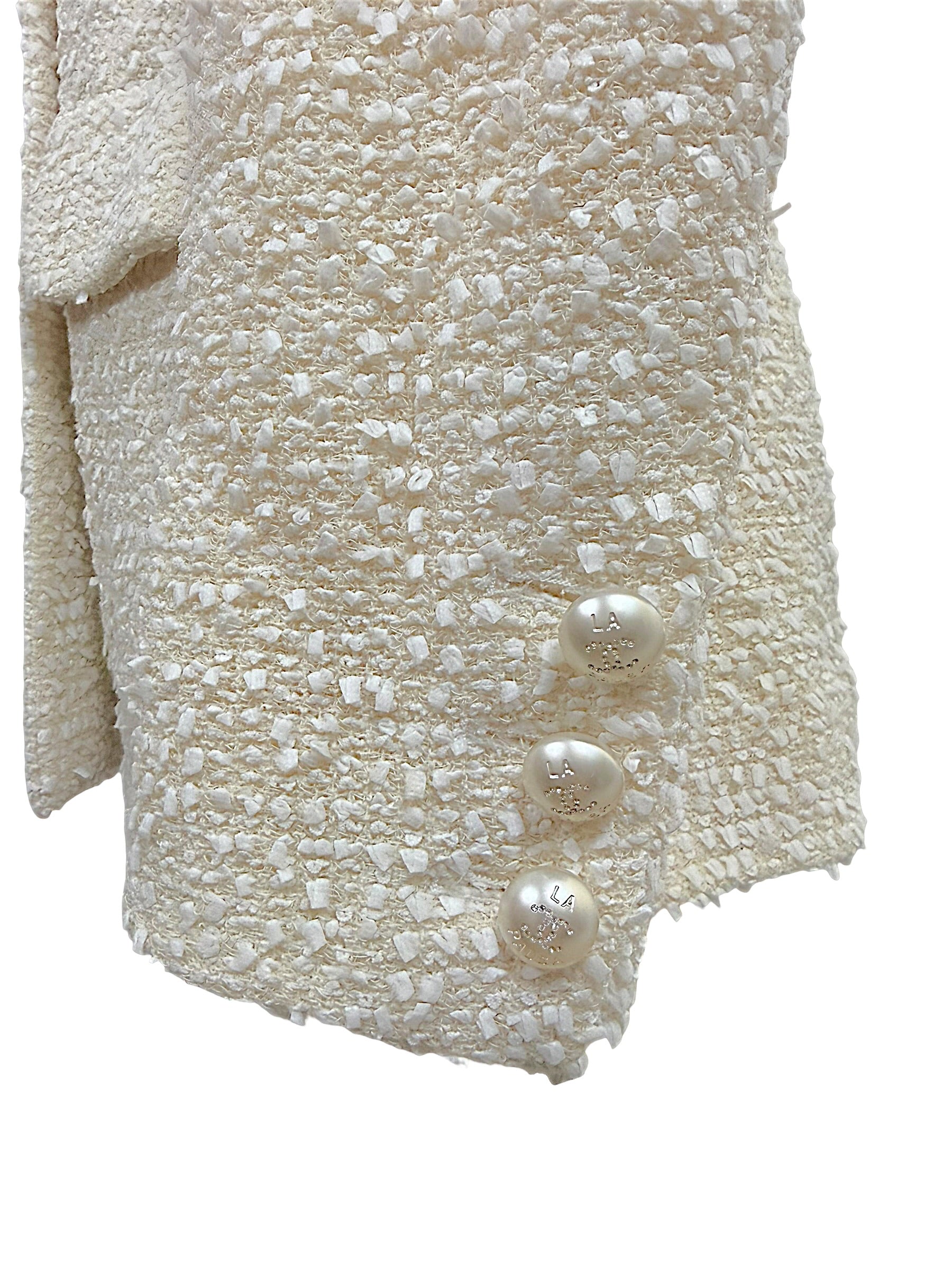 Close-up of the three original pearl-effect La Pausa CC buttons adorning the sleeve cuff of the authentic Chanel Cruise 2019 Runway Look 26 ivory fantasy tweed jacket.