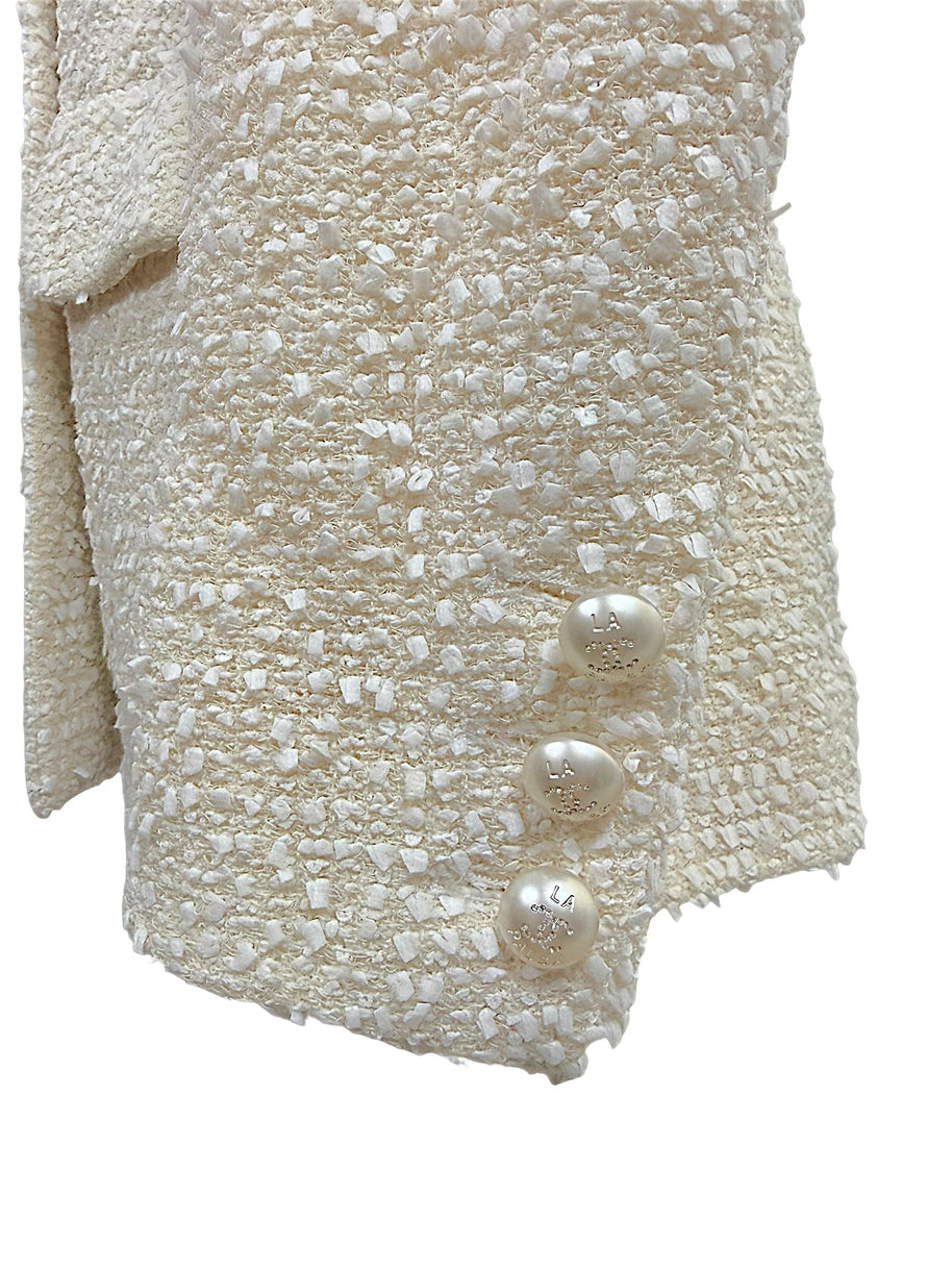 Close-up of the three original pearl-effect La Pausa CC buttons adorning the sleeve cuff of the authentic Chanel Cruise 2019 Runway Look 26 ivory fantasy tweed jacket.