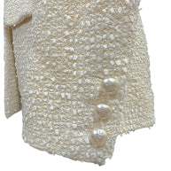 Close-up of the three original pearl-effect La Pausa CC buttons adorning the sleeve cuff of the authentic Chanel Cruise 2019 Runway Look 26 ivory fantasy tweed jacket.