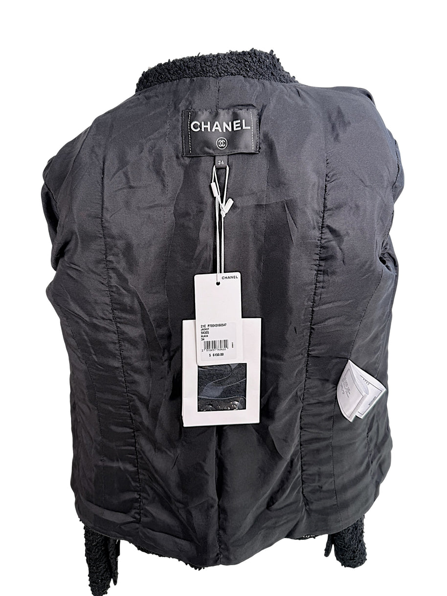 Interior view of Chanel Cruise 2021 black bouclé jacket showing Chanel boutique tags and silk lining