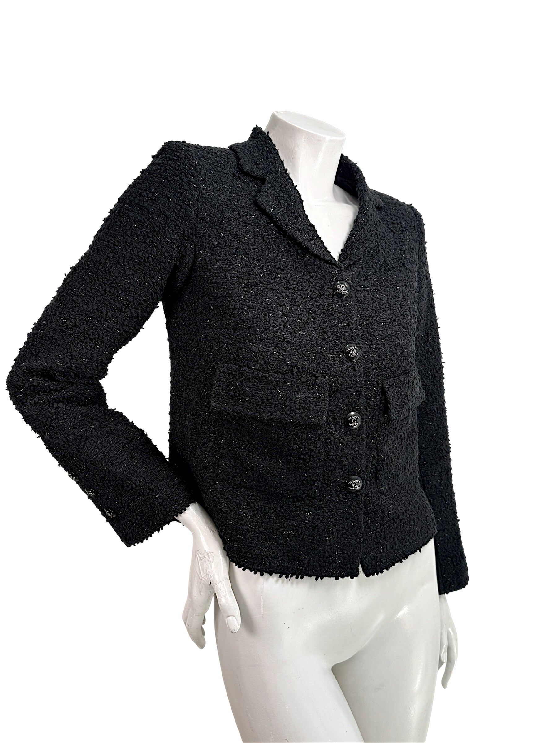 Angled front view of Chanel Cruise 2021 black bouclé tweed runway jacket with flap pockets and tailored silhouette