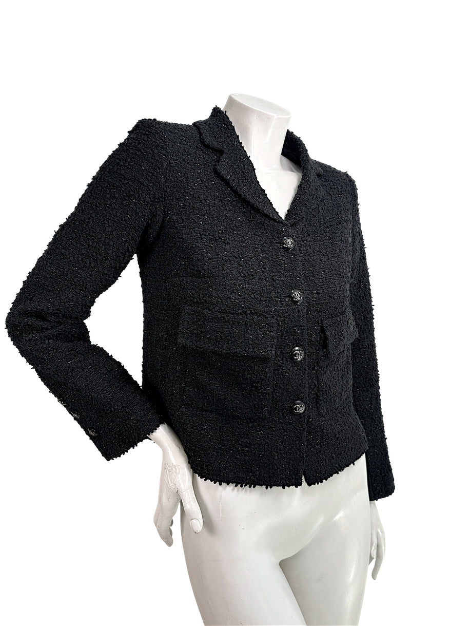 Angled front view of Chanel Cruise 2021 black bouclé tweed runway jacket with flap pockets and tailored silhouette