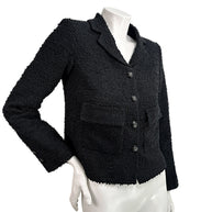 Angled front view of Chanel Cruise 2021 black bouclé tweed runway jacket with flap pockets and tailored silhouette