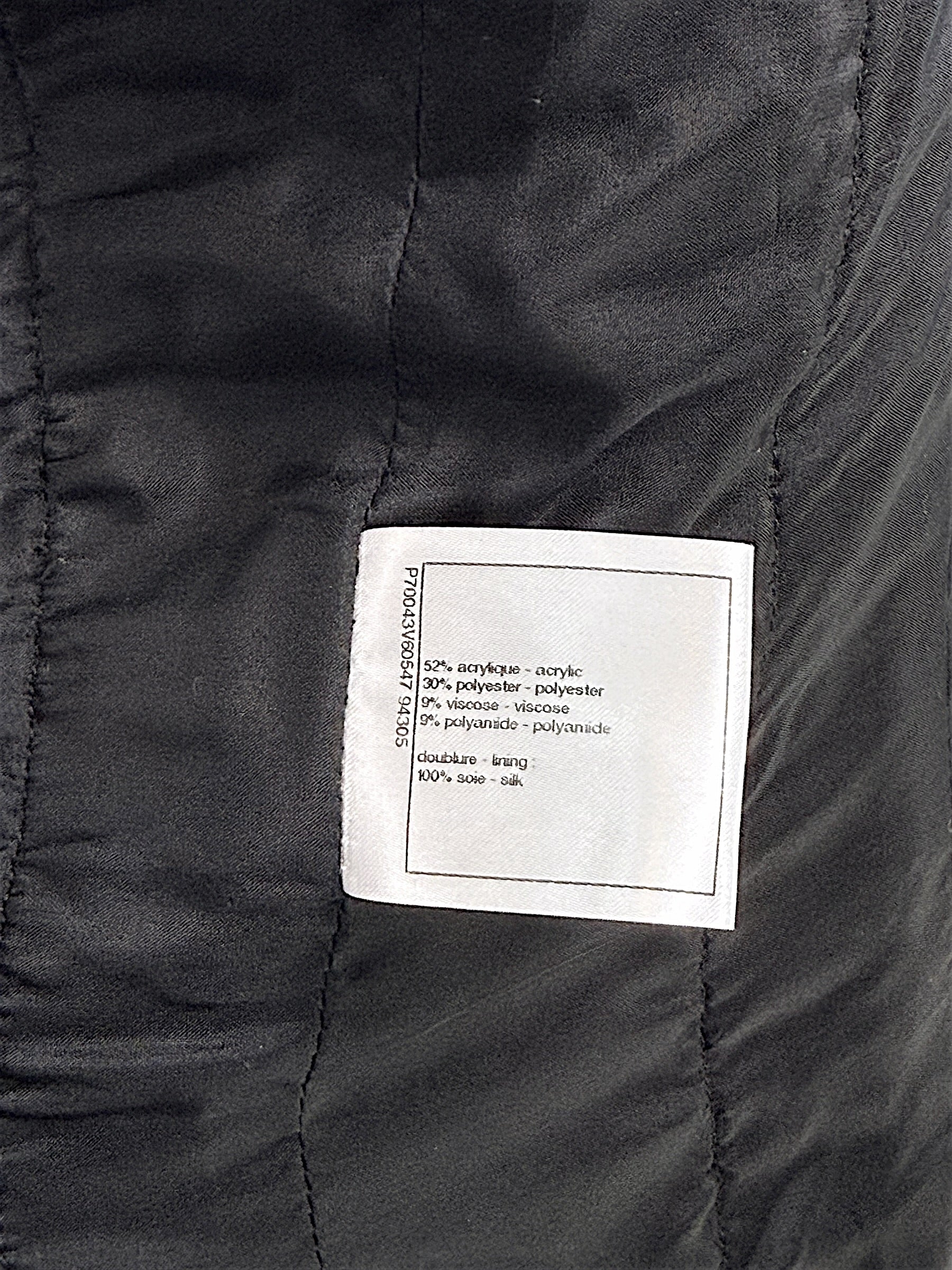 Fabric composition label inside Chanel Cruise 2021 black bouclé tweed jacket with silk lining