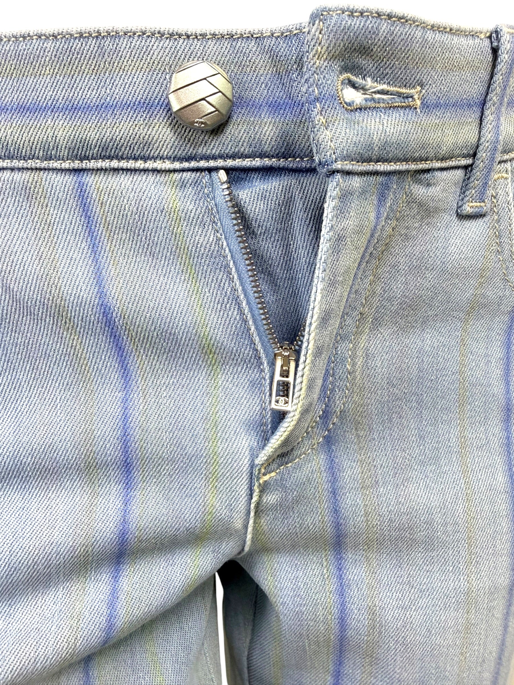 Detail image of Chanel striped denim jeans zip fly closure with engraved hardware and light blue denim finish.