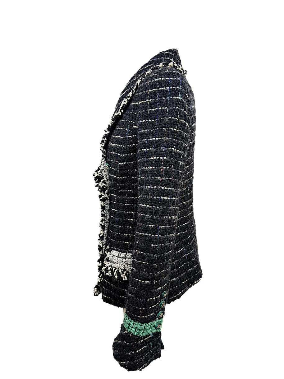 Right side profile of the Chanel Fall 2009 Runway Look 22 black bouclé tweed jacket featuring ivory fringe trim, emerald cuff detail, and signature Chanel tailoring.