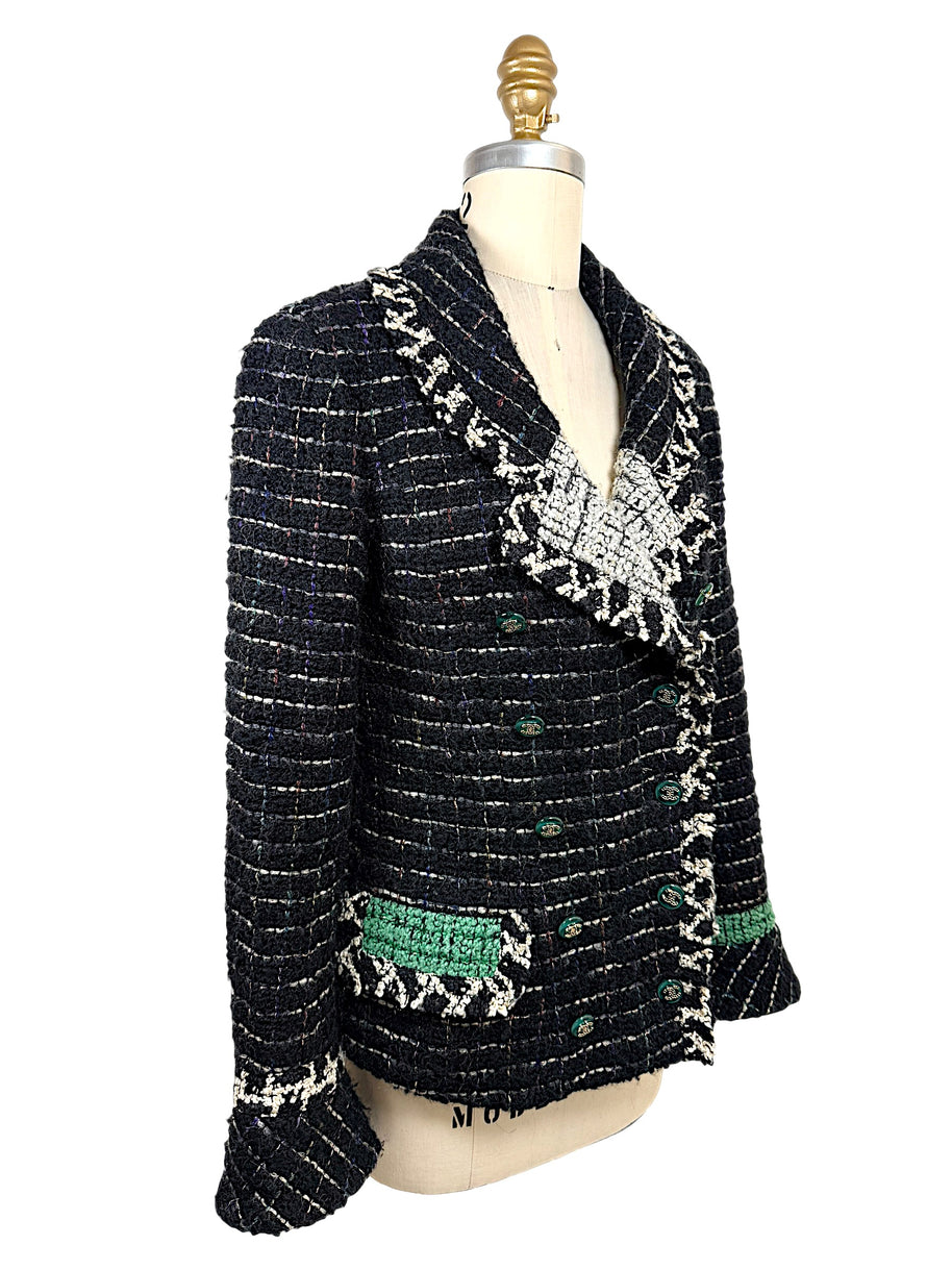 Three-quarter view of Chanel Fall 2009 Runway Look 22 black fantasy tweed jacket highlighting textured bouclé weave, emerald pocket detail, and sculptural shawl collar.