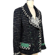Three-quarter view of Chanel Fall 2009 Runway Look 22 black fantasy tweed jacket highlighting textured bouclé weave, emerald pocket detail, and sculptural shawl collar.
