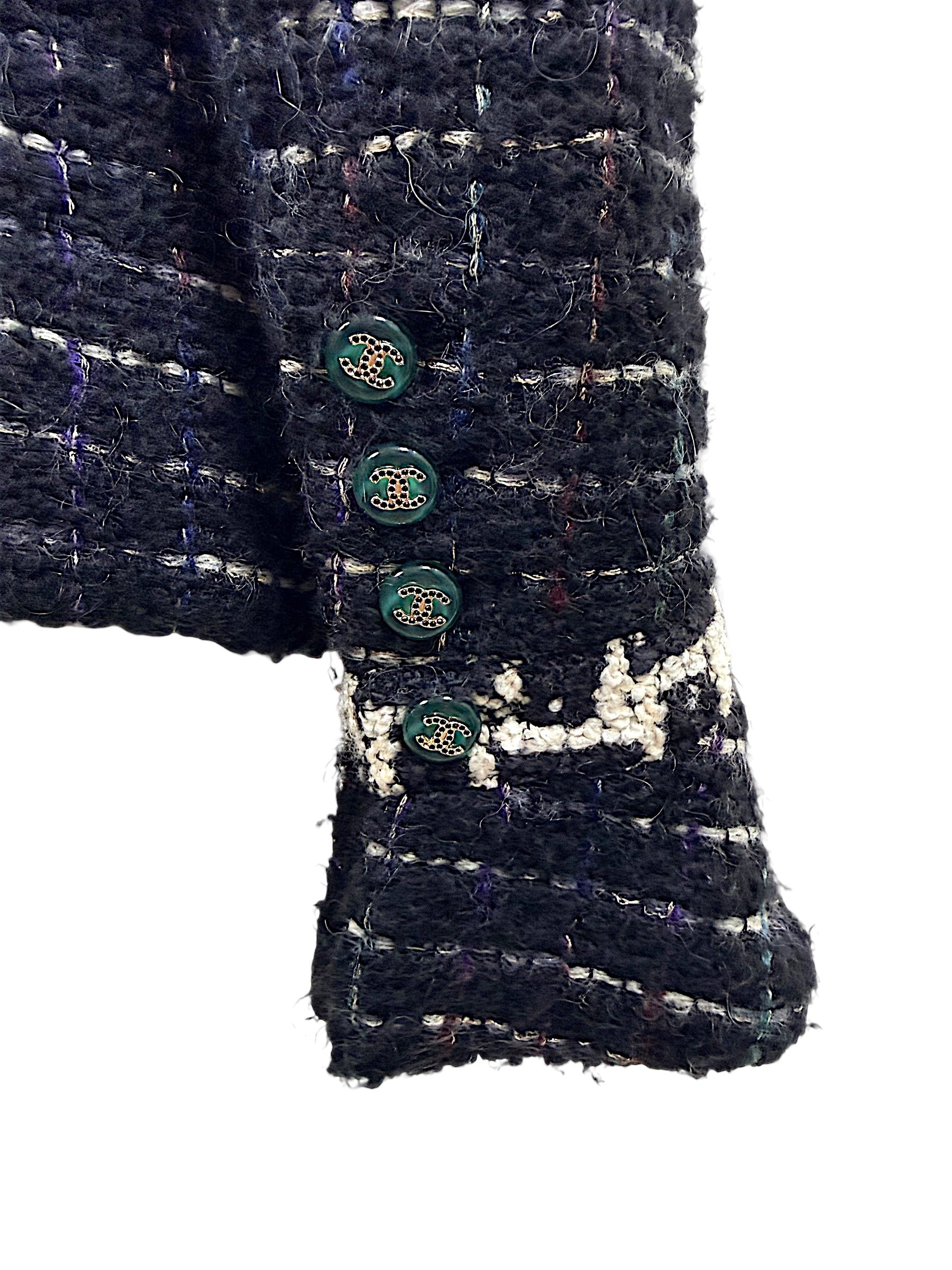 Close-up of Chanel emerald enamel CC logo buttons and textured bouclé cuff from the Fall 2009 Runway Look 22 jacket.