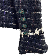 Close-up of Chanel emerald enamel CC logo buttons and textured bouclé cuff from the Fall 2009 Runway Look 22 jacket.