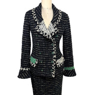 Front view of Chanel Fall 2009 Runway Look 22 black bouclé tweed jacket and matching skirt featuring ivory fringe trim, emerald green accents, and signature CC buttons.