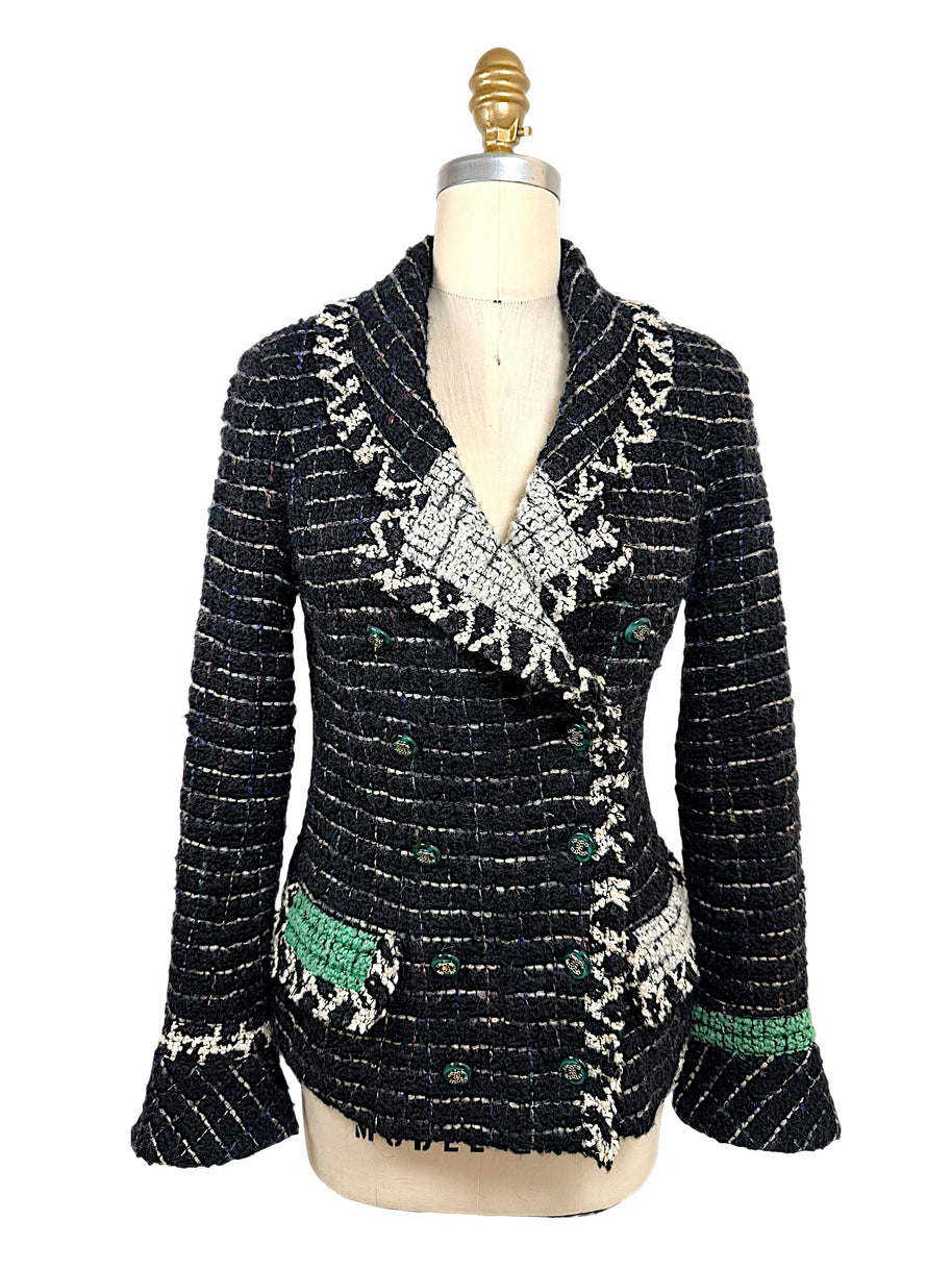 Front view of Chanel Fall 2009 Runway Look 22 black bouclé tweed jacket with shawl collar, ivory fringe trim, emerald green woven accents, and enamel CC buttons.