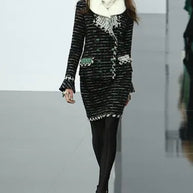 Documented Chanel Fall 2009 Runway Look 22 as presented on the runway under Karl Lagerfeld, featuring the original styling with oversized emerald tweed hat, ivory fur collar, and matching black bouclé tweed skirt suit.