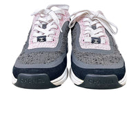 Front view of Chanel pink and grey tweed sneakers with CC lace tabs and Chanel toe branding