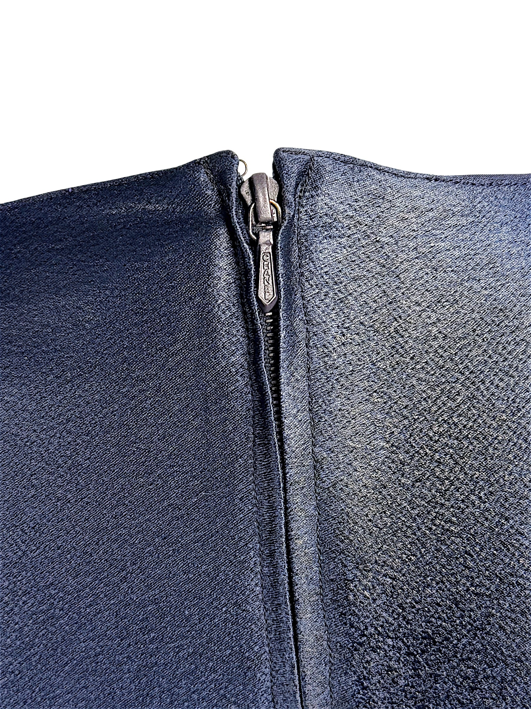 Close-up detail of vintage Chanel navy metallic garment zipper closure and textured fabric finish.