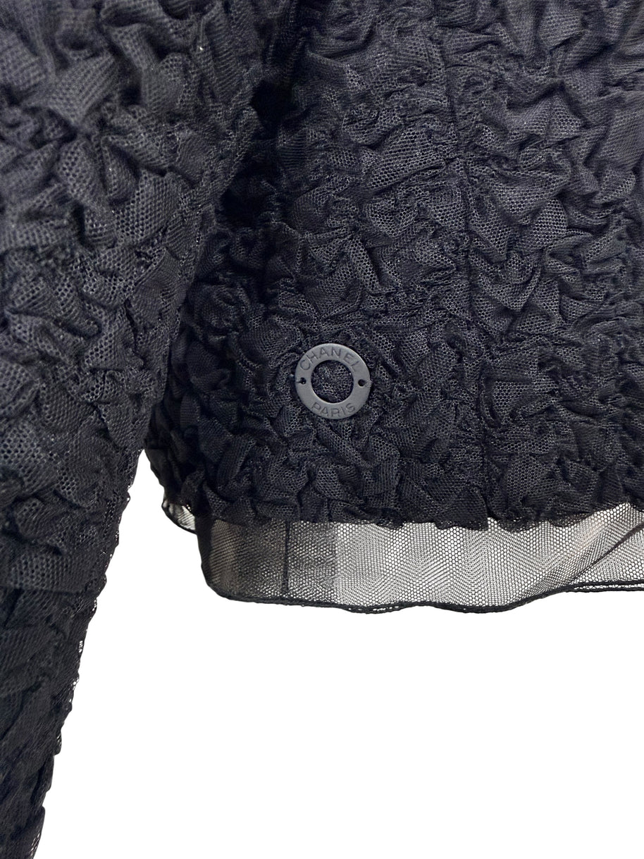 Close-up of Chanel Paris button detail on black ruched textured bolero jacket