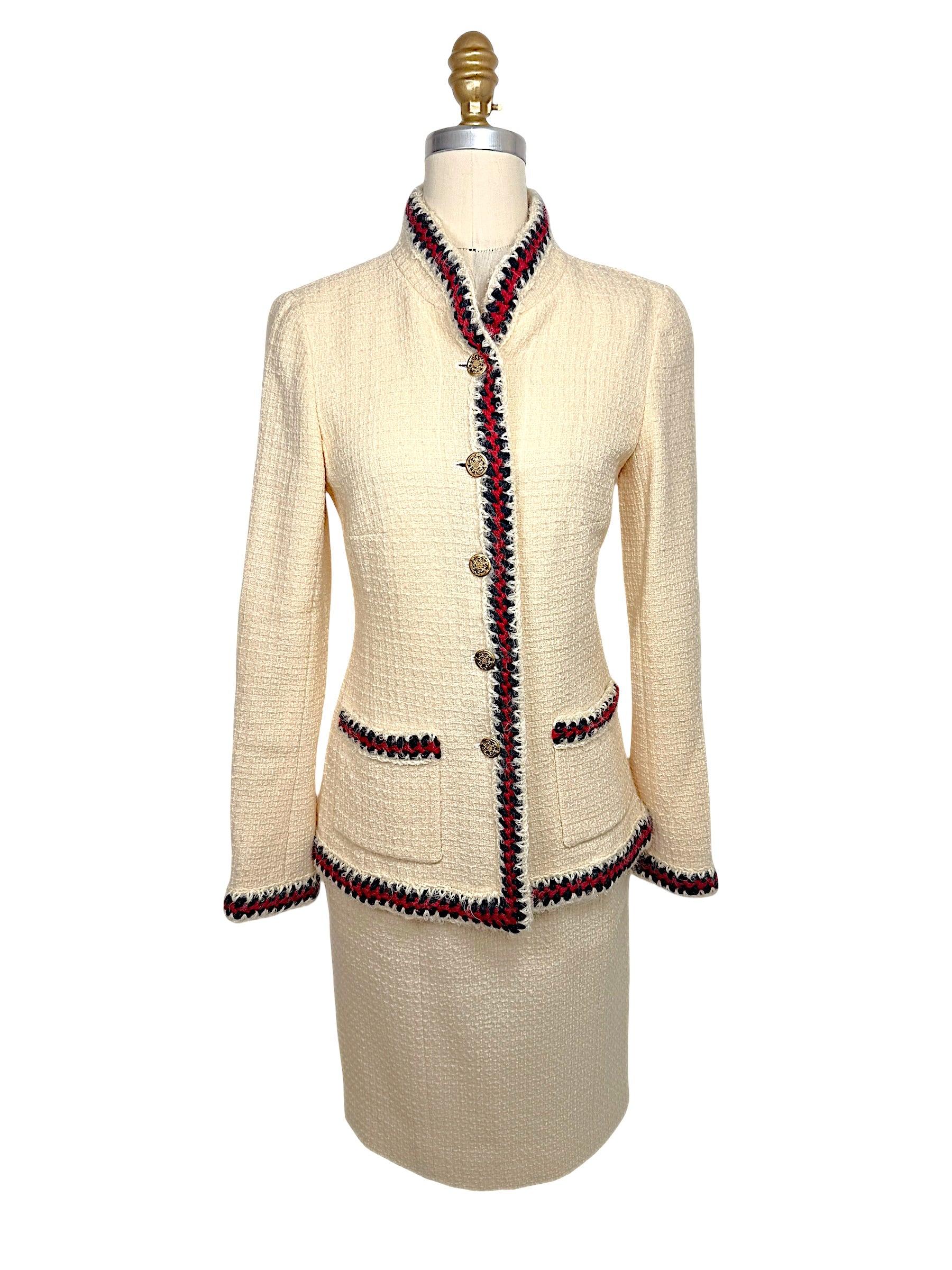 Front view of Chanel Pre-Fall 2010 Paris-Shanghai Runway Look 42 ivory bouclé jacket and matching pencil skirt with navy and crimson braided trim and gold-tone logo buttons.