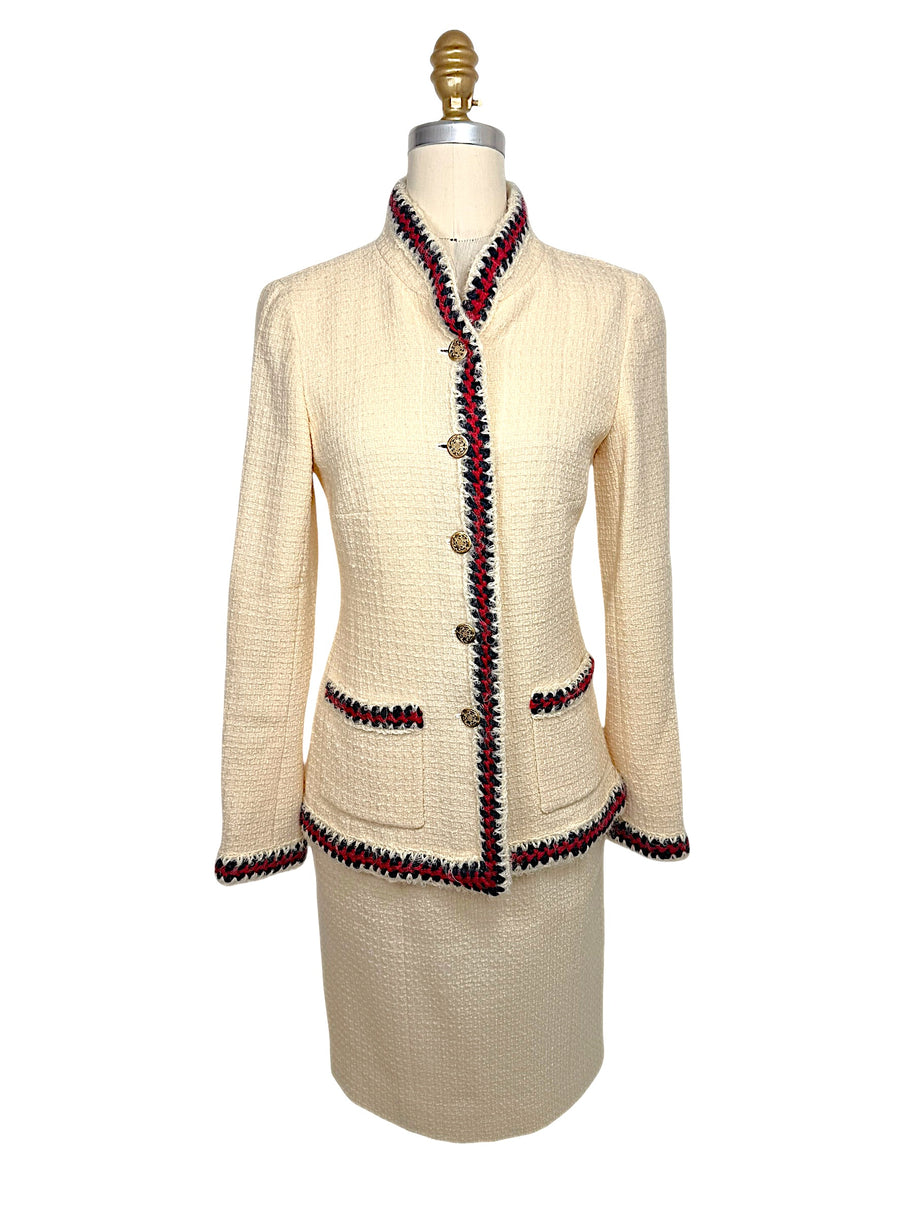 Front view of Chanel Pre-Fall 2010 Paris-Shanghai Runway Look 42 ivory bouclé jacket and matching pencil skirt with navy and crimson braided trim and gold-tone logo buttons.