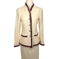 Front view of Chanel Pre-Fall 2010 Paris-Shanghai Runway Look 42 ivory bouclé jacket and matching pencil skirt with navy and crimson braided trim and gold-tone logo buttons.