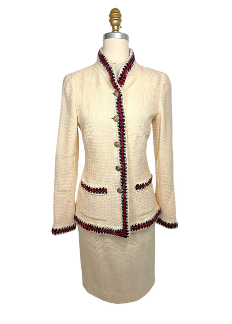Front view of Chanel Pre-Fall 2010 Paris-Shanghai Runway Look 42 ivory bouclé jacket and matching pencil skirt with navy and crimson braided trim and gold-tone logo buttons.