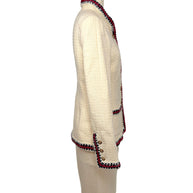 Side profile of Chanel Pre-Fall 2010 ivory bouclé jacket showing structured tailoring and braided trim extending around the hem and cuffs.