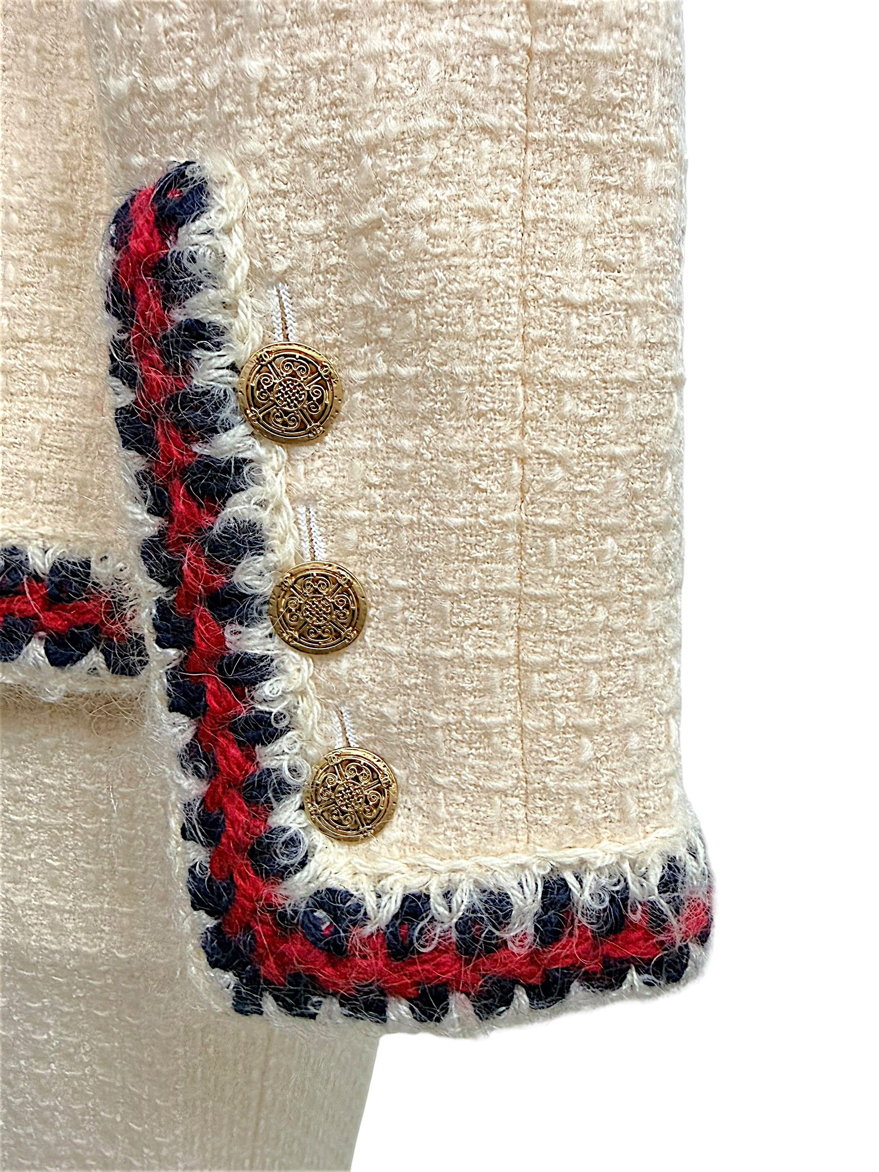 Close-up of Chanel Pre-Fall 2010 jacket sleeve featuring braided trim and decorative gold-tone logo buttons.