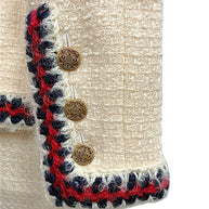 Close-up of Chanel Pre-Fall 2010 jacket sleeve featuring braided trim and decorative gold-tone logo buttons.