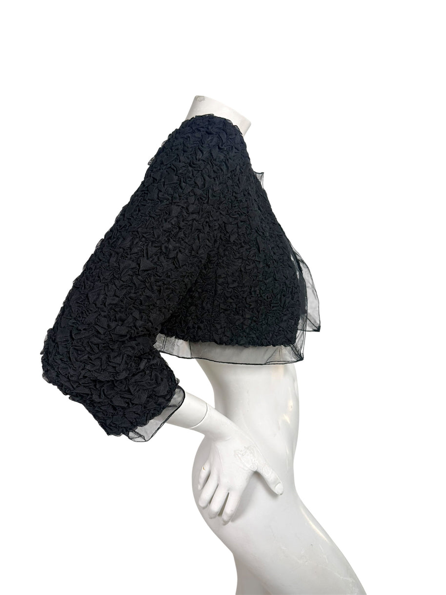 Right side view of Chanel black cropped bolero jacket with textured ruched fabric and sheer sleeve