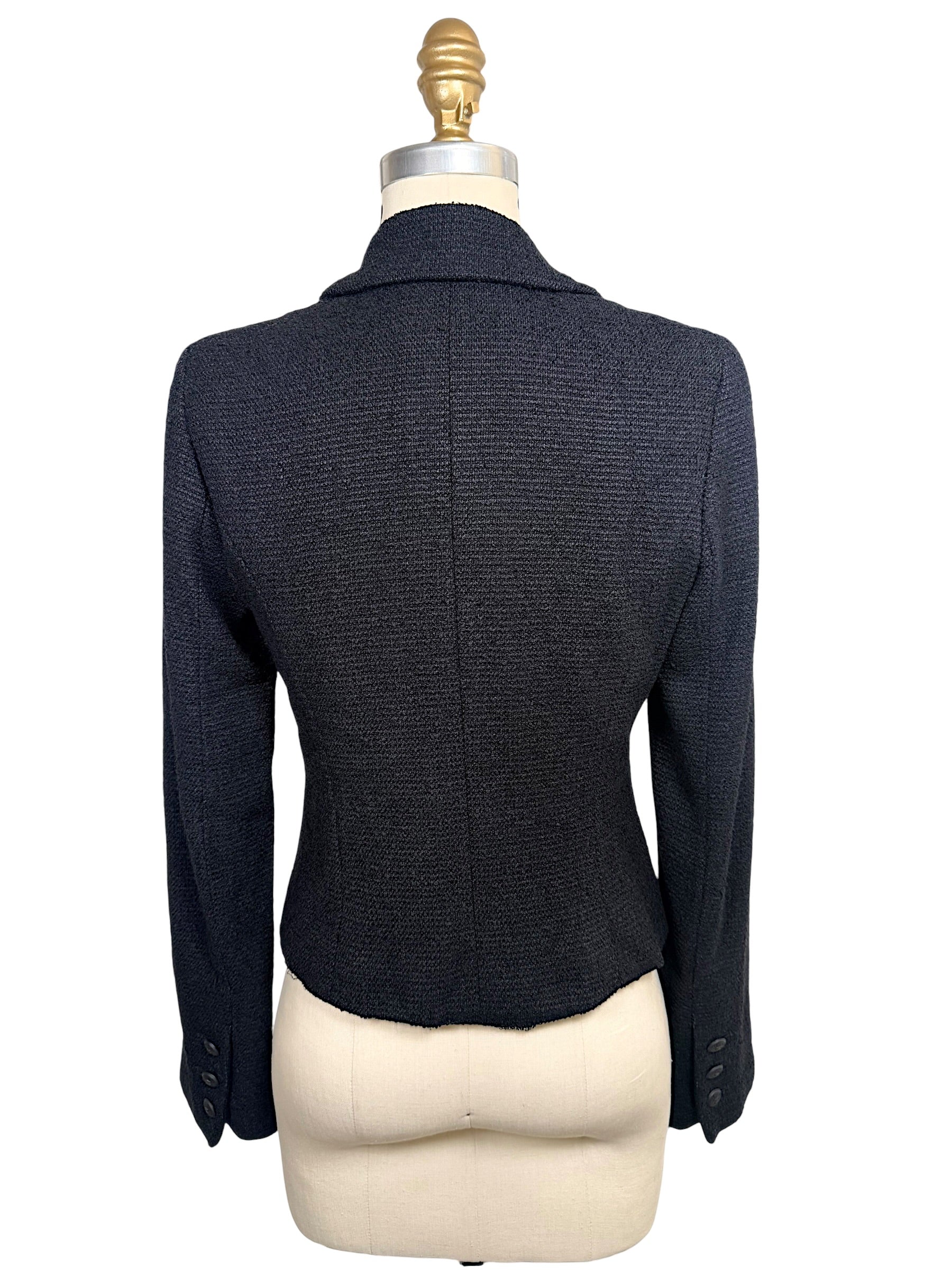 Rear view of Chanel Spring 2005 runway black bouclé cropped jacket highlighting tailored back construction and fitted silhouette.