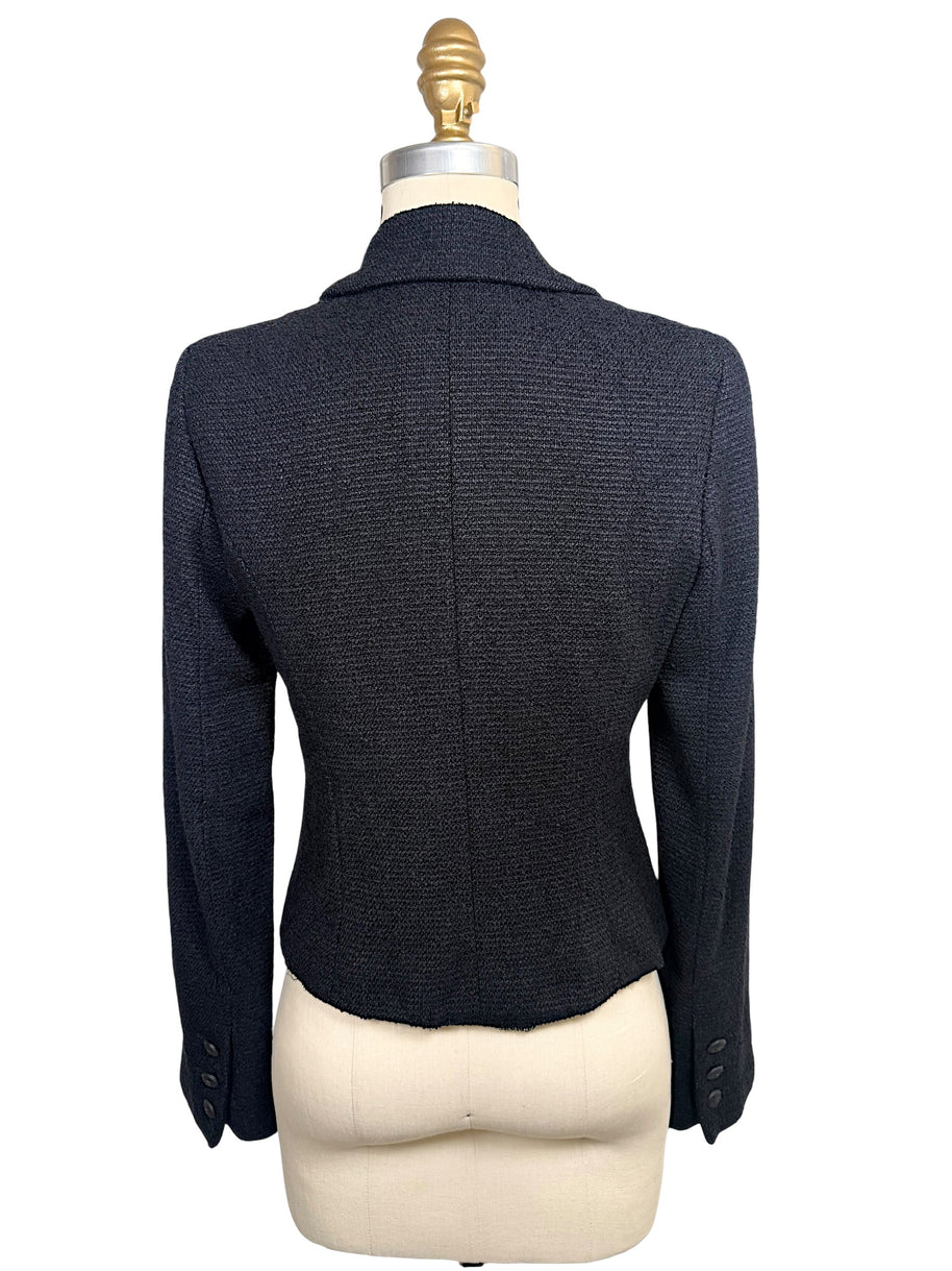 Rear view of Chanel Spring 2005 runway black bouclé cropped jacket highlighting tailored back construction and fitted silhouette.
