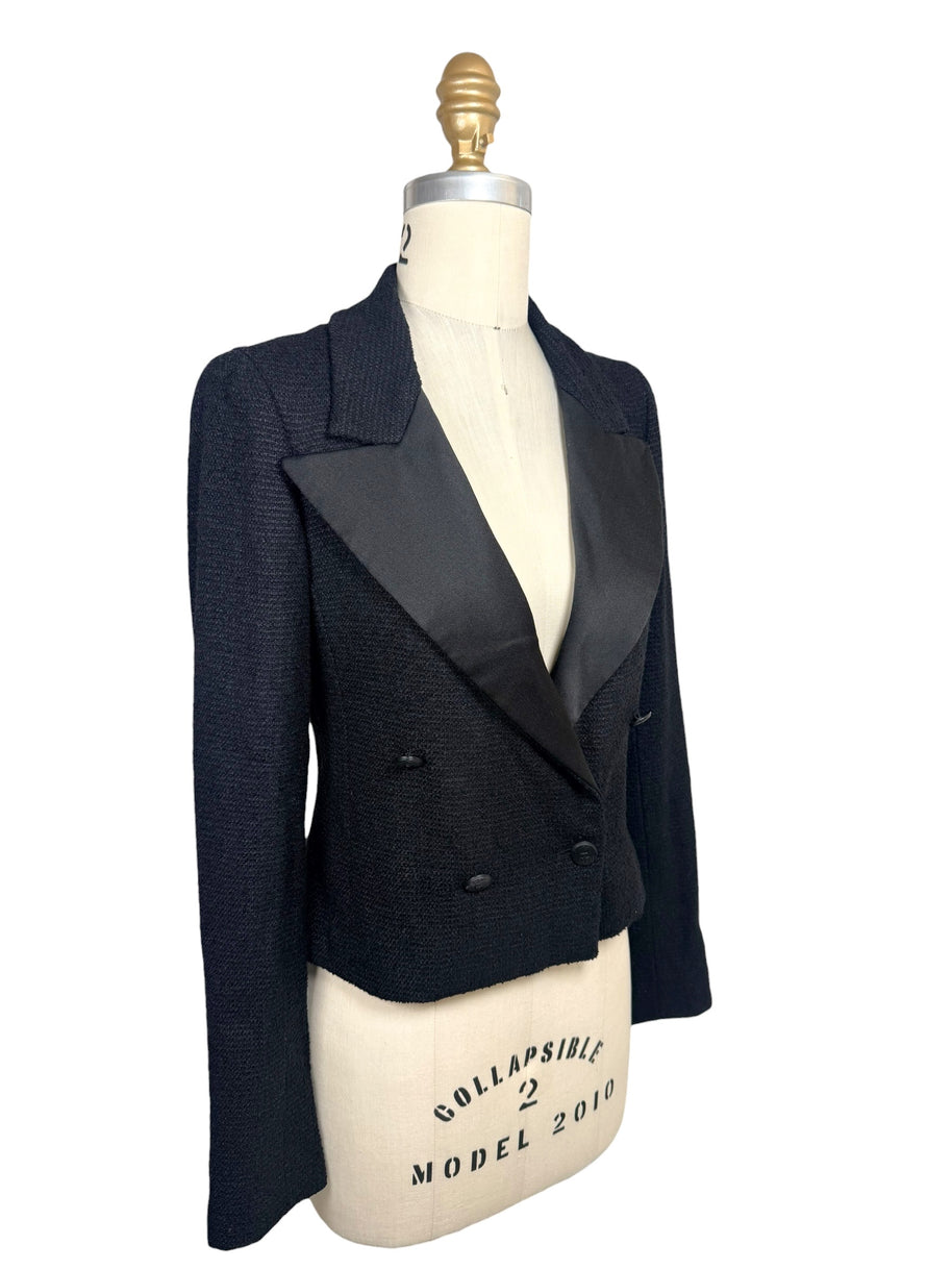 Three-quarter front view of Chanel Spring 2005 runway cropped black bouclé tuxedo jacket with oversized satin lapels and engraved CC buttons.