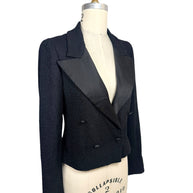Three-quarter front view of Chanel Spring 2005 runway cropped black bouclé tuxedo jacket with oversized satin lapels and engraved CC buttons.